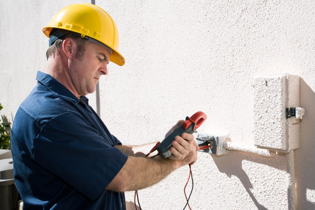 Electrician using a meter to check the voltage on an outdoor receptacle.  Model is a licensed master electrican and all work is performed according to  industry code and safety standards.